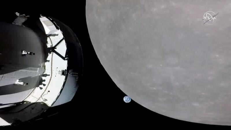 This screengrab from NASA TV shows NASA's Orion capsule, left, nearing the moon, right,...